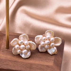 Detail of baroque pearl flower earrings on champagne silk background