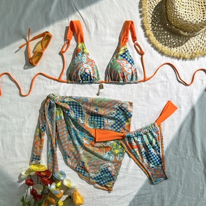Three-piece paisley print bikini set with matching sarong and orange halter top detail