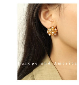 Close-up of elegant gold woven earrings with pearl inlay worn by a female model