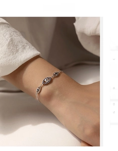 Detail of S925 silver bracelet featuring three blue evil eye charms on a model's wrist