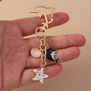 Detail of metal dolphin keychain featuring shell, dolphin and starry starfish charms