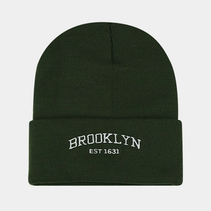 Detail of white Brooklyn embroidery on a dark green knit beanie with folded cuff