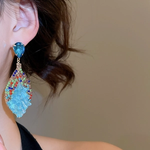 Macro shot of bohemian crystal drop earrings with blue stones on a model's ear