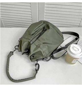Detail of army green nylon bucket bag with drawstring closure and front zipper pocket