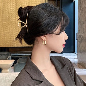 Detailed side view of minimalist gold twisted hair clip and round stud earrings on a model