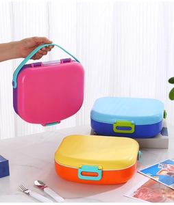 Three colorful 5-compartment portable lunch boxes with handles on marble surface