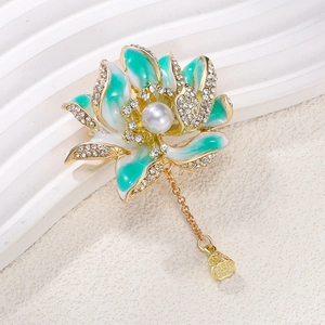 Macro detail of enamel lotus brooch with green petals, pearls, and hanging seed pod