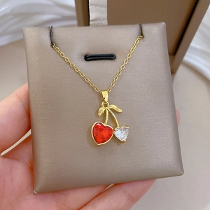 Detail of gold cherry pendant with red heart gemstone and sparkling clear zircons