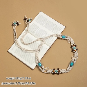 Détail d'une ceinture bohème tissée avec perles en bois et turquoise sur un livre ouvert