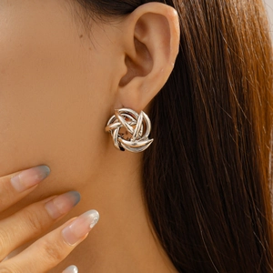 Detailed close-up of a silver geometric spiral flower stud earring on a female model