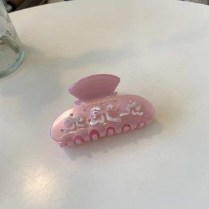 Détail d'une pince à cheveux rose en acétate avec motif flocon et strass brillants