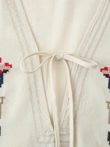 Detail von V-Ausschnitt mit Kordelzug und bunter Blumenstickerei auf beige Baumwollleinen