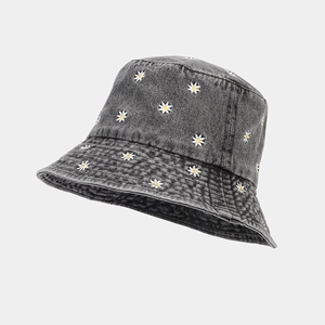 Detailed embroidery of white daisies on washed denim bucket hat with stitching texture