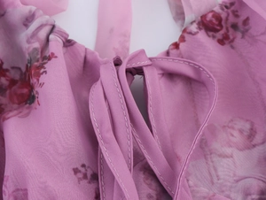Detail of floral organza dress showing neck tie knot and purple flower print texture