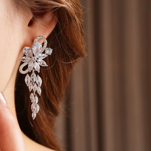 Close-up of sparkling flower tassel earrings with zircons worn by a female model