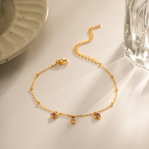 Vue détaillée d'un collier doré avec des pendentifs ronds roses et carrés violets