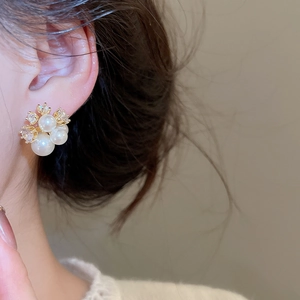 Detailed view of elegant pearl cluster earrings with gold plating and zircons on ear