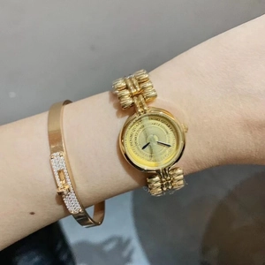 Close-up of golden vintage-style wristwatch and matching bracelet on a female wrist