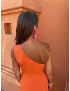 Détail d'un body orange à une épaule avec des boucles d'oreilles fleurs roses