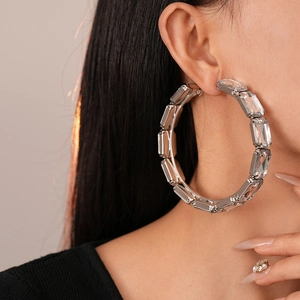 Gros plan de boucles d'oreilles créoles argentées avec cristaux portées par un mannequin
