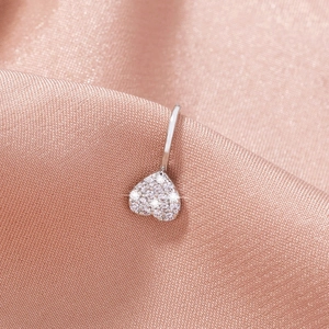 Macro shot of silver heart-shaped navel piercing with pavé crystals on pink silk fabric
