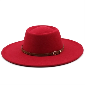 Detail of red wool fedora hat featuring a brown leather strap and metal buckle