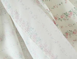 Dettaglio del tessuto a fiori con cuciture overlock rifinite sul vestito bianco