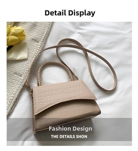 Detail view of beige crocodile embossed crossbody bag with a woven handle and tulip accent