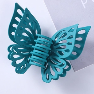 Detail of teal matte butterfly hair claw clip with intricate hollowed-out wing design