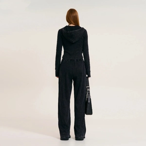 Back view of a woman wearing a vintage-style black hooded sweatshirt and wide-leg joggers