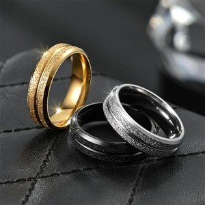 Detailed close-up of matte titanium steel rings in gold, black, and silver on leather
