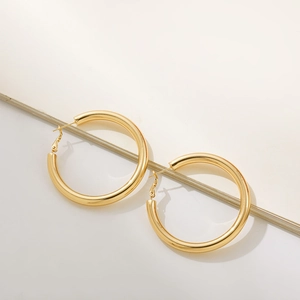 Close-up of chunky gold hoop earrings with a high-polish 18K finish and thick tube design