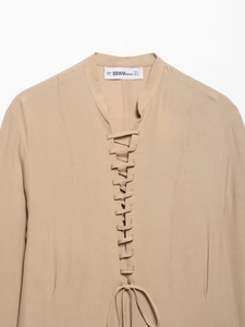 Detailed view of beige chiffon dress neckline with lace-up design and brand size label