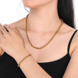 Detailed close-up of golden pearl chain necklace and bracelet set on female model