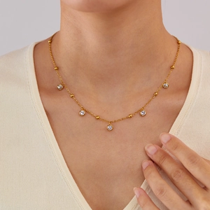 Close-up of elegant gold necklace with five zircon pendants on model's neckline