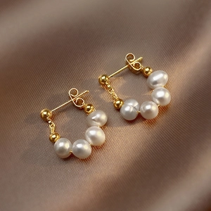French vintage baroque pearl stud earrings with gold metal accents on brown silk