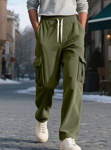 Detailed texture of olive green corduroy cargo pants with drawstring and large side pockets