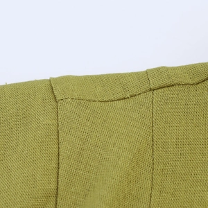 Detailed macro view of the linen texture and stitching on a green sleeveless dress