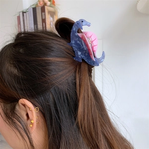 Detail of blue marble dinosaur hair claw clip styled on long brunette hair