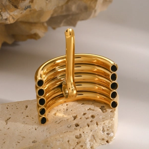Macro shot of gold multi-layered tubular ring on minimalist stone display stand