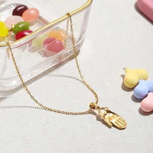 Détail macro du pendentif torse féminin et paume en plaqué or 18k sur une chaîne fine