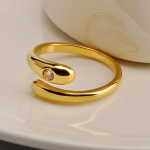 Macro shot of gold snake-style ring with sparkling zircon stone on a white ceramic plate