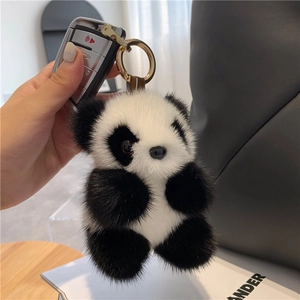 Cute mink fur panda plush keychain with golden ring on a luxury leather handbag