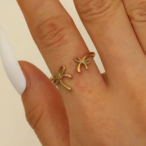 Detailed close-up of a golden bow-shaped open ring on a model's middle finger