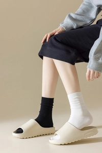 Détail de chaussettes mi-hautes en coton côtelé noir et blanc avec des chaussons beiges