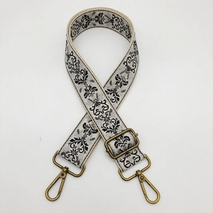 Detail of adjustable floral embroidery bag strap with vintage brass swivel hooks and buckle