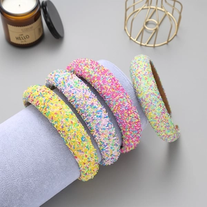 Detail of four colorful glitter headbands with candy textures on a purple display stand