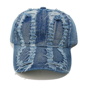 Close-up of distressed denim baseball cap with heavy ripped details and frayed textures