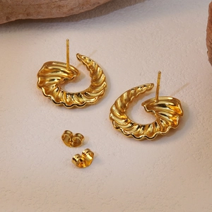 Detail of gold horn-shaped earrings with spiral texture and butterfly backs