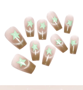 Detail of coffin-shaped gradient cat-eye fake nails with green star accents